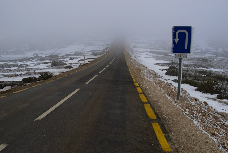 Road leading into mist, with a U-Turn sign to the right.